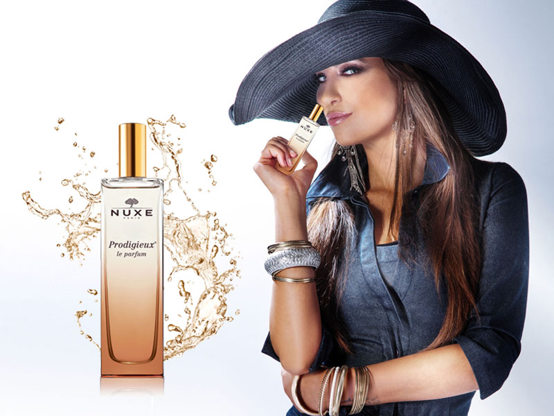 Portrait of beautiful young woman wearing hat, smelling perfume.